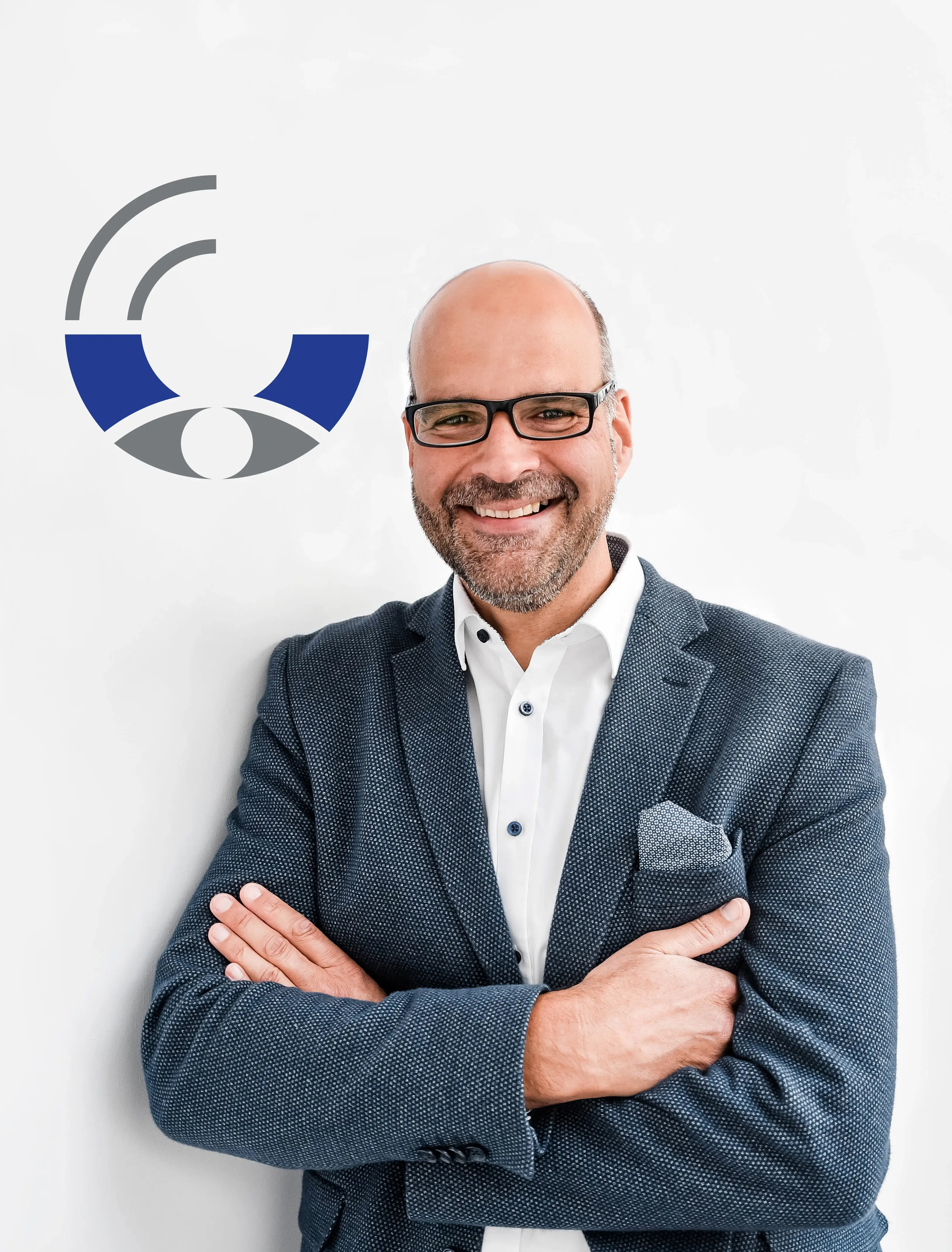 Ein Photo von Jens Boelen, sympathisches Lächeln, verschränkte Arme vor einer weißen Wand